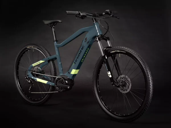 Una bicicleta eléctrica de montaña Haibike HardNine 5.0, diseñada para aventuras en terrenos desafiantes. Su cuadro de aluminio azul con detalles amarillos integra componentes Bosch de alto rendimiento y ruedas de 29", ideal para explorar senderos.