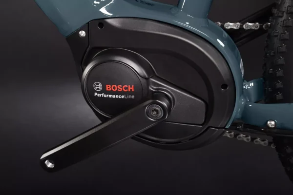 Una bicicleta eléctrica de montaña Haibike HardNine 5.0, diseñada para aventuras en terrenos desafiantes. Su cuadro de aluminio azul con detalles amarillos integra componentes Bosch de alto rendimiento y ruedas de 29", ideal para explorar senderos.