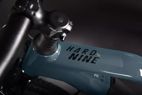 Una bicicleta eléctrica de montaña Haibike HardNine 5.0, diseñada para aventuras en terrenos desafiantes. Su cuadro de aluminio azul con detalles amarillos integra componentes Bosch de alto rendimiento y ruedas de 29", ideal para explorar senderos.
