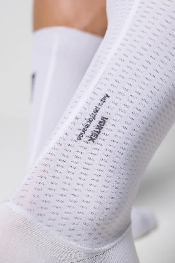 En la lucha contra el crono, todo detalle importa. Hemos diseñado estos calcetines con una altura prolongada dentro de los estándares UCI, con un tejido perforado de baja resistencia al viento, que ofrece una regulación de temperatura óptima. La impresión interior de silicona garantiza su adherencia creando un efecto segunda piel, que también contribuye a la aerodinámica al prescindir del clásico dobladillo
