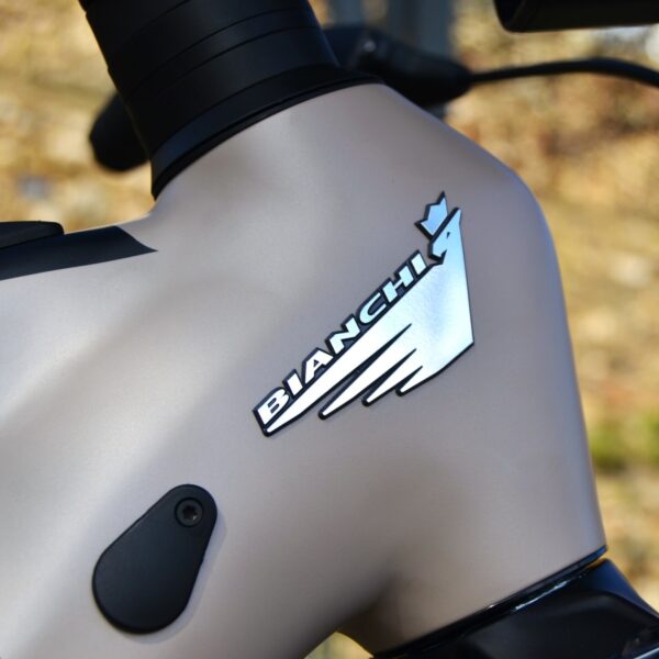 Bicicleta eléctrica de montaña Bianchi E-Vertic FX-Type con doble suspensión, motor central integrado y neumáticos Schwalbe Nobby Nic, estacionada en un entorno rural.