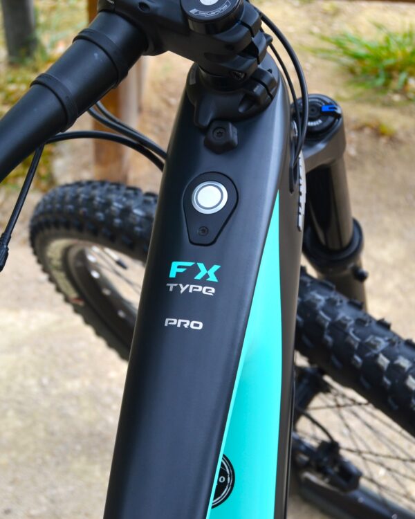 Bicicleta eléctrica de montaña Bianchi T-Tronik FX Pro 29" XT RockShox ZEB con doble suspensión, motor central integrado y neumáticos Schwalbe Nobby Nic, estacionada en un entorno rural.
