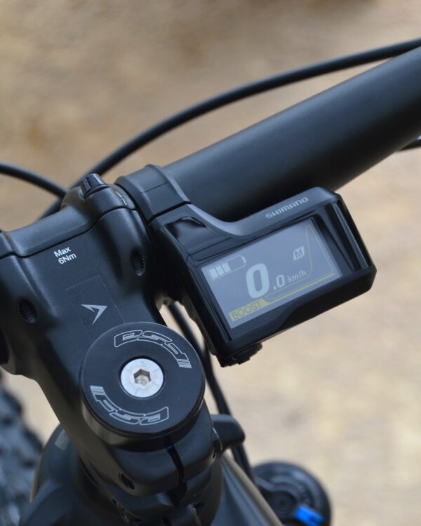 Bicicleta eléctrica de montaña Bianchi T-Tronik FX Pro 29" XT RockShox ZEB con doble suspensión, motor central integrado y neumáticos Schwalbe Nobby Nic, estacionada en un entorno rural.