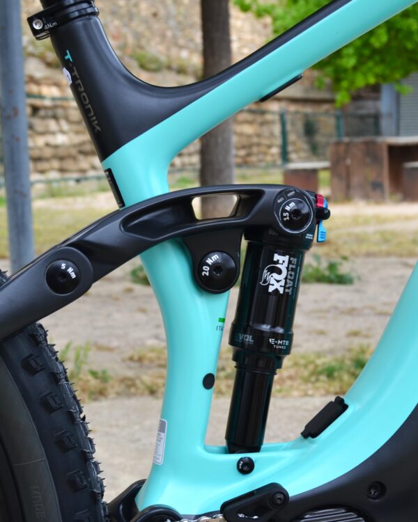 Bicicleta eléctrica de montaña Bianchi T-Tronik FX Pro 29" XT RockShox ZEB con doble suspensión, motor central integrado y neumáticos Schwalbe Nobby Nic, estacionada en un entorno rural.