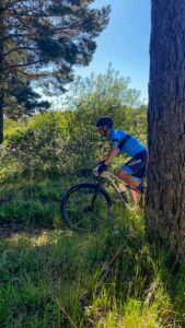 Ciclistas del equipo Bikes Moncayo atravesando un sendero boscoso durante la carrera, rodeados de vegetación y con vistas al Moncayo.
