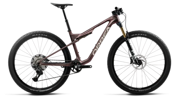 La Orbea Oiz M20 2027 es una bicicleta de montaña de carbono diseñada para ofrecer velocidad, control y eficiencia en rutas de cross-country, rally y maratón MTB. Su cuadro de carbono OMR, las suspensiones FOX Factory de 120 mm, la transmisión Shimano XT de 12 velocidades y las ruedas OQUO forman un montaje de alto rendimiento para ciclistas que buscan máxima eficacia tanto en las subidas como en los descensos técnicos.